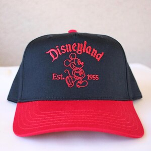 K&ouml;nnte beinhalten: Schwarze und rote Baseballkappe mit einem roten gestickten Mickey Mouse und dem Text "Disneyland Est. 1955".