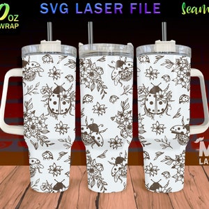 May include: A white 40 ounce stainless steel tumbler with a black and white design of ladybugs and flowers. The tumbler has a handle and a lid with a straw.