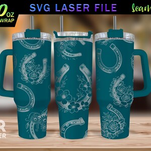 May include: A teal blue 40 ounce tumbler with a white horseshoe and floral design. The tumbler has a handle and a lid. The text "40 oz FULL WRAP" is visible in the image.