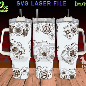 May include: A white 40 ounce tumbler with a handle and a straw. The tumbler has a seamless design featuring a repeating pattern of vintage cameras and flowers. The text "SVG LASER FILE" and "Seamless" are visible at the top of the image.