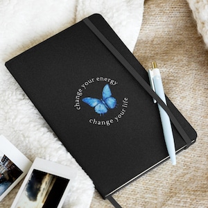 May include: Black journal with a blue butterfly graphic and the text "change your energy change your life".