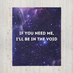 May include: A throw blanket with a deep space design in shades of purple, blue, and white. The blanket features the text "IF YOU NEED ME, I'LL BE IN THE VOID" in white, centered on the blanket. The blanket is rectangular.