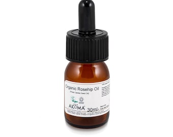 May include: A 30 ml amber glass bottle of organic rosehip oil with a black dropper top. The bottle label is white with black text that reads "Organic Rosehip Oil (Rosa Canina Seed Oil)". The label also features a green vegan logo and the brand name "AKOMA Skincare".