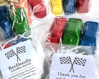 Könnte beinhalten: Ein Set mit vier kleinen, autoförmigen Buntstiften in Rot, Gelb, Blau und Grün, verpackt in durchsichtigen Cellophanbeuteln mit weißem, zerkleinertem Papier. Die Beutel sind mit Schnur gebunden und haben ein kleines weißes Etikett mit dem Text "BeeDoodle Coloring Crayons" und einem handgefertigten Rezept. Ein weiteres Etikett lautet "Vielen Dank, dass du meinen Geburtstag mit mir gefeiert hast! -Greyson".