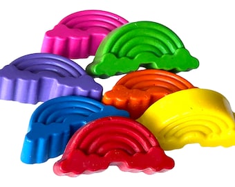 May include: A set of six rainbow-shaped crayons, each with a different color: pink, green, purple, orange, blue, and red.