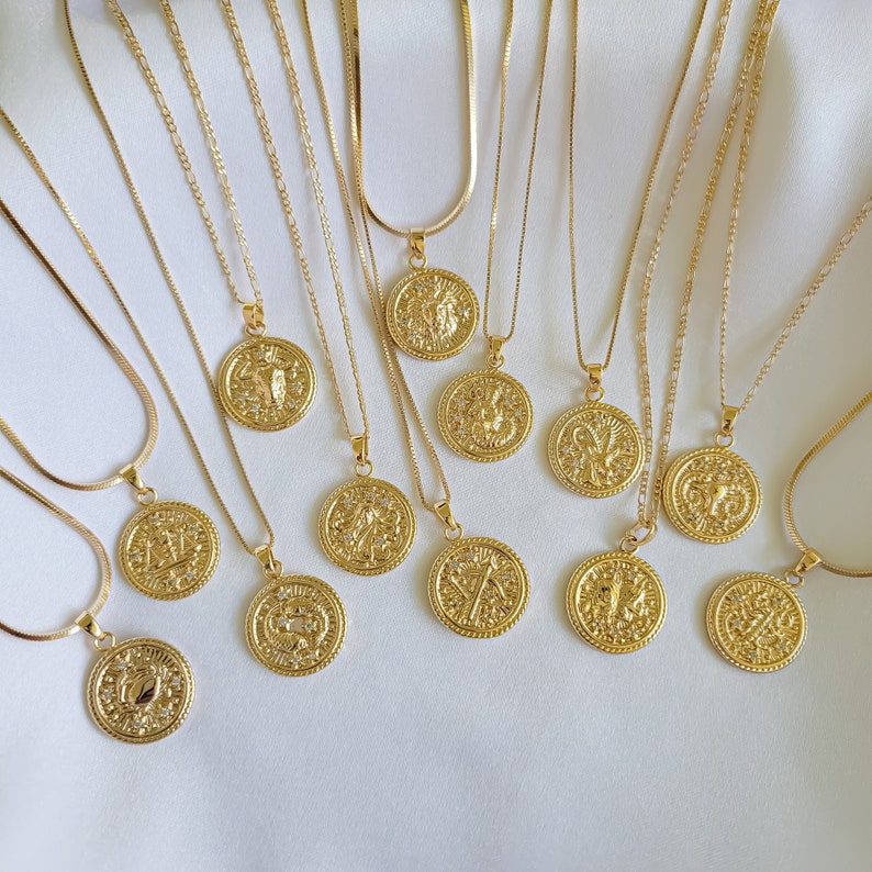Puede incluir: Doce collares de oro con s&iacute;mbolos del zod&iacute;aco en colgantes redondos. Cada colgante presenta un signo del zod&iacute;aco diferente.