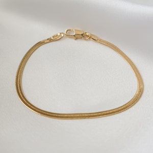 May include: A gold snake chain bracelet with a clasp closure.