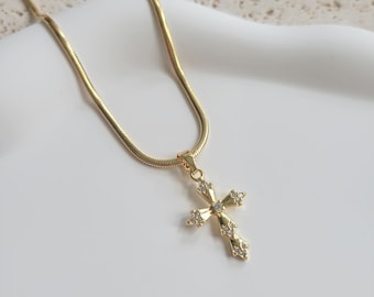 May include: A gold chain necklace with a small, sparkly cross pendant.