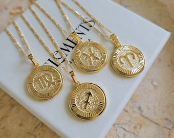 May include: Four gold necklaces with zodiac signs pendants. The pendants are round and feature the zodiac signs for Virgo, Pisces, Aries, and Sagittarius. The necklaces are on a white background with the word "Elements" printed on the surface.