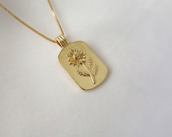 May include: A gold chain necklace with a pendant featuring a detailed embossed flower design.