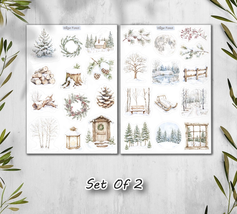 May include: Two sheets of winter-themed stickers with watercolor illustrations. The stickers feature snowy trees, wreaths, cabins, and a full moon. The text "Winter Forest" is at the top of each sheet, and "Set Of 2" is at the bottom.