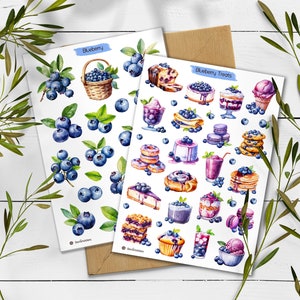 May include: Two white sticker sheets featuring watercolor illustrations. One sheet labeled Blueberry displays various clusters of fresh blueberries and a woven basket. The second sheet labeled Blueberry Treats shows desserts like cakes, pancakes, and ice cream topped with blueberries.