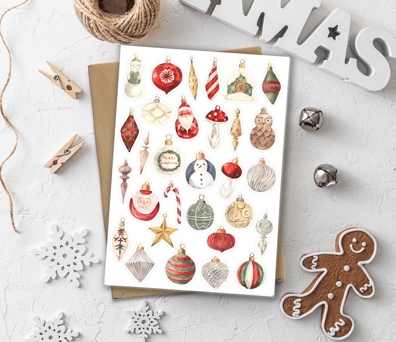 Puede incluir: Una hoja de pegatinas de adornos navide&ntilde;os con varios dise&ntilde;os, incluyendo un mu&ntilde;eco de nieve, Pap&aacute; Noel y un hombre de jengibre. Los adornos son de color rojo, verde, dorado y blanco. Las pegatinas est&aacute;n sobre un fondo blanco con elementos decorativos.