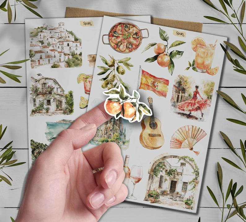 May include: Watercolor stickers with Spanish themes. Illustrations include paella, oranges, a Spanish flag, a flamenco dancer, a guitar, and architectural scenes. The word "Spain" is written on the stickers.
