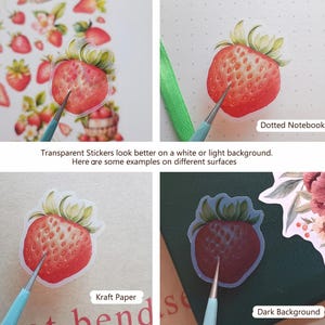 May include: A set of transparent strawberry stickers shown on various surfaces including a dotted notebook, kraft paper, and a dark background. The stickers feature a detailed red strawberry illustration with green leaves and a clear adhesive border.