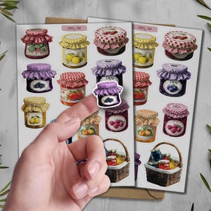 May include: A sheet of stickers featuring various jam jar designs. The jars have different colored lids and labels, with illustrations of fruits like cherries, lemons, and berries. Some stickers are in baskets.