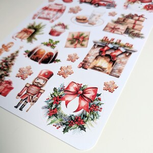 May include: A sticker sheet featuring various Christmas-themed illustrations including a nutcracker, a wreath with a red bow, a fireplace with stockings, wrapped gifts, a red truck, a sweater, a gingerbread man, and snowflake-shaped cookies.