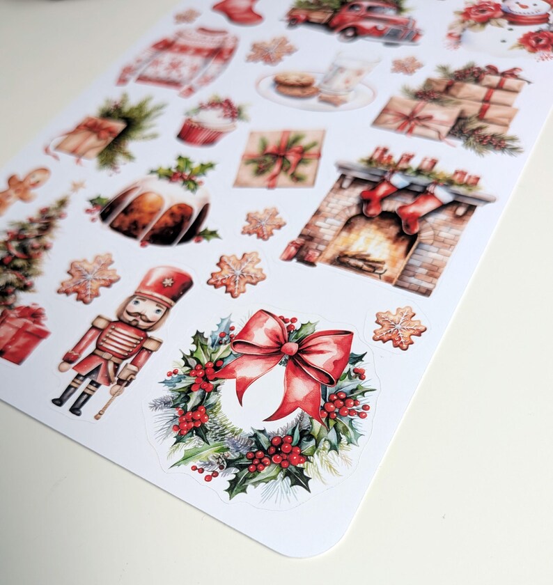 May include: A sticker sheet featuring various Christmas-themed illustrations including a nutcracker, a wreath with a red bow, a fireplace with stockings, wrapped gifts, a red truck, a sweater, a gingerbread man, and snowflake-shaped cookies.