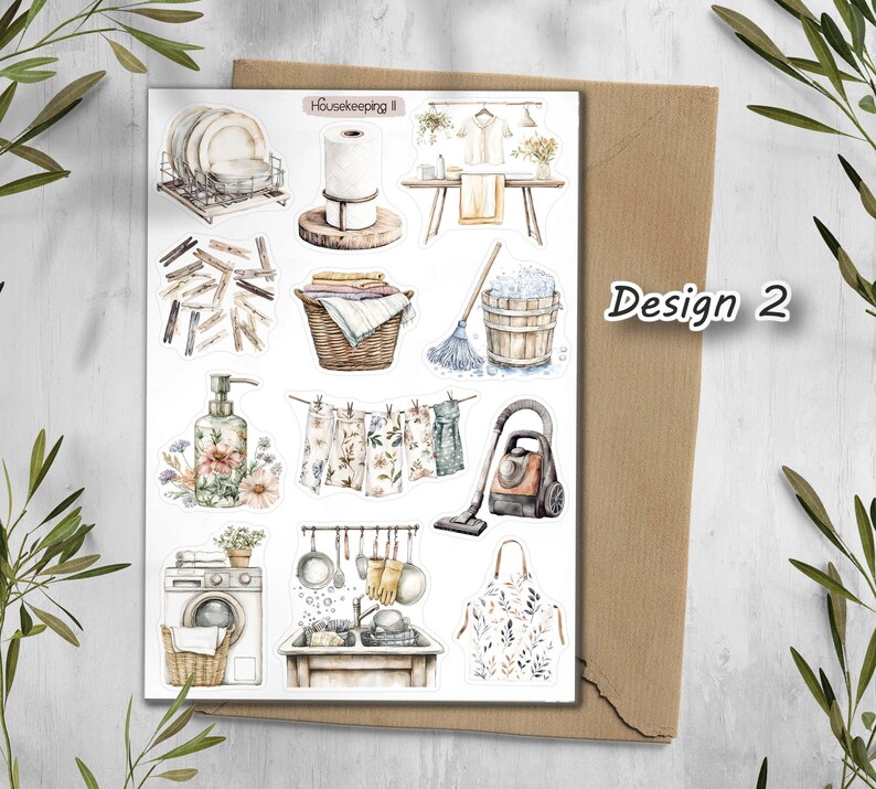 May include: A sticker sheet with watercolor illustrations of household items, including dishes, laundry, cleaning supplies, and a washing machine. The text "Housekeeping II" is at the top, and "Design 2" is on the right side.