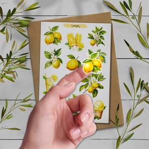 May include: A sheet of stickers featuring watercolor illustrations of lemons, lemon trees, lemon popsicles, and a glass of lemonade. The stickers are on a brown background and the text "Lemon" is at the top of the sheet.