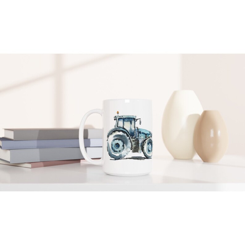 K&ouml;nnte beinhalten: Eine wei&szlig;e Keramiktasse mit einer Aquarell-Illustration eines blauen Traktors. Der Traktor hat eine schwarze Kabine und gro&szlig;e R&auml;der.