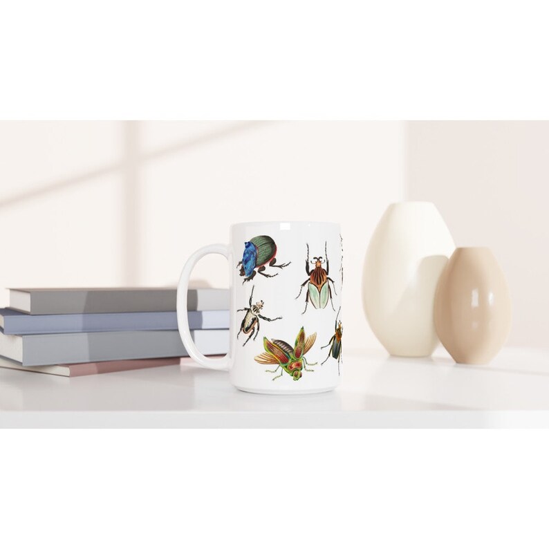 Puede incluir: Taza de cer&aacute;mica blanca con una ilustraci&oacute;n colorida de varios escarabajos. Los escarabajos est&aacute;n representados en un estilo realista con detalles intrincados.