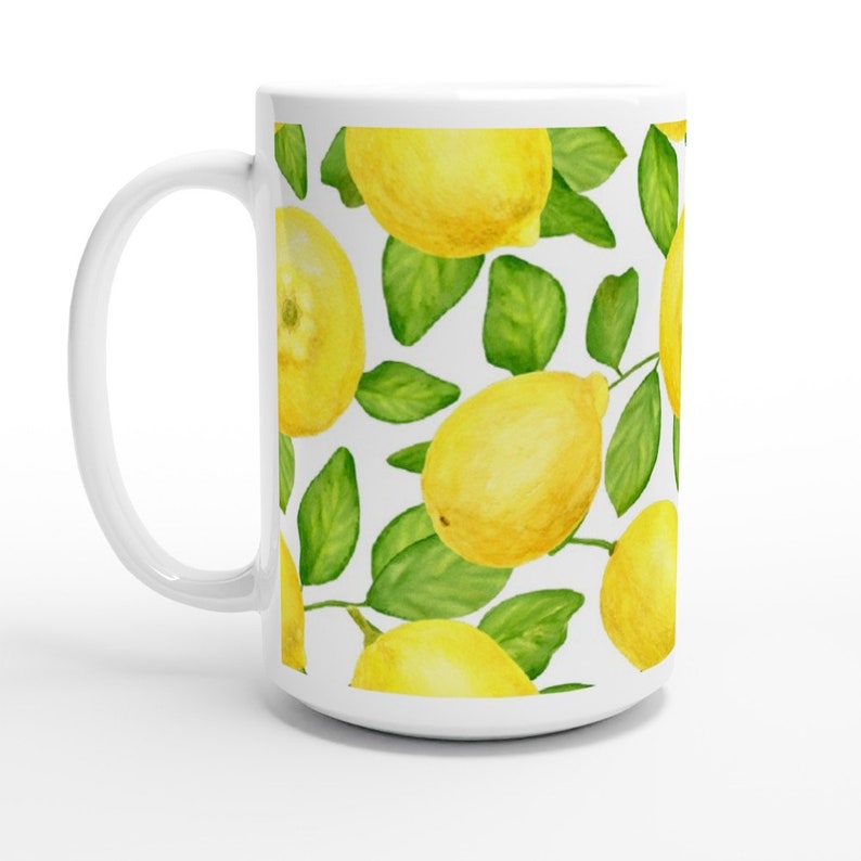 K&ouml;nnte beinhalten: Wei&szlig;e Keramiktasse mit Zitronenmuster. Die Tasse zeigt gelbe Zitronen und gr&uuml;ne Bl&auml;tter auf wei&szlig;em Hintergrund.