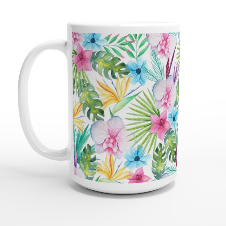 May include: White ceramic mug featuring a tropical floral pattern. The design incorporates pink, blue, yellow, and green flowers and leaves.