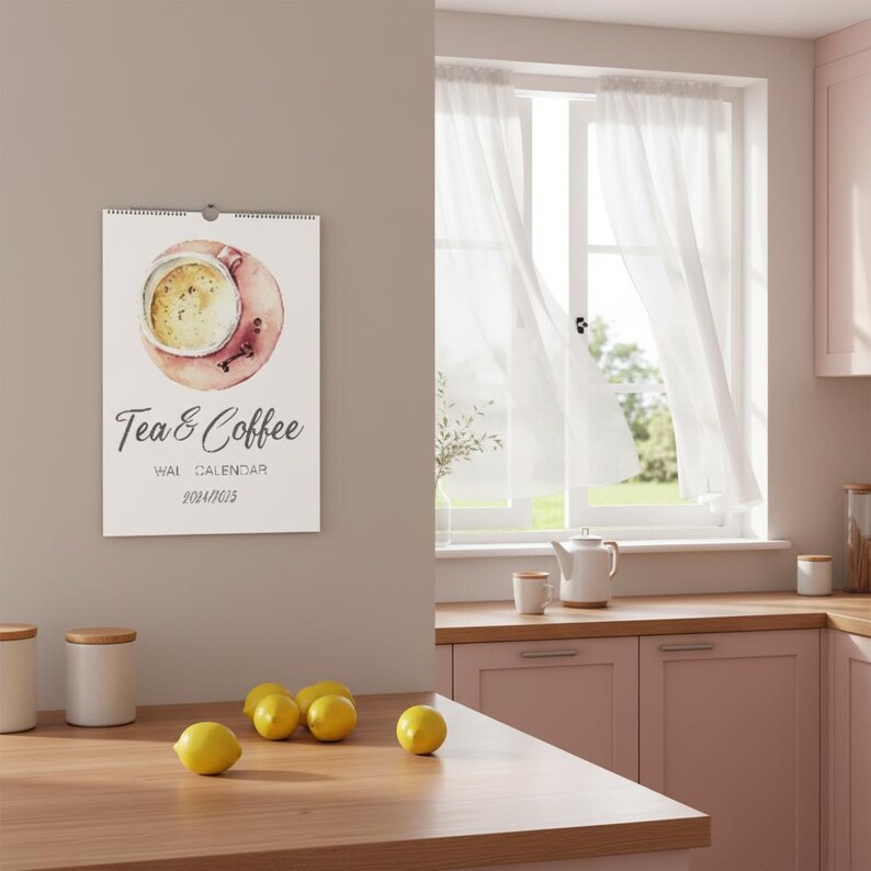 Peut inclure: Un calendrier mural pr&eacute;sentant une illustration &agrave; l'aquarelle d'une tasse de caf&eacute;, avec le texte Tea & Coffee WALL CALENDAR 2024/2025 imprim&eacute; en dessous. Le calendrier est blanc avec une reliure spirale en haut et est fix&eacute; au mur.