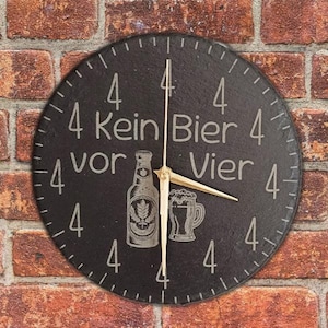 Könnte beinhalten: Eine runde, schwarze Uhr mit weißen Ziffern und Zeigern. Das Zifferblatt zeigt den Text "Kein Bier vor Vier" und Illustrationen einer Bierflasche und eines Bierkrugs. Die Uhr befindet sich vor einer Backsteinmauer.