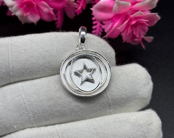 May include: A silver pendant with a star design inside a circle. The pendant has a textured surface and is on a white background.