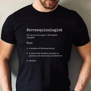 May include: A black t-shirt with white text that defines the word "ferroequinologist" as a person who studies railways, especially locomotives. The text includes the phonetic pronunciation of the word and the definition.