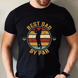 Puede incluir: Camiseta negra con un gráfico retro de un golfista y el texto "Best Dad By Par".