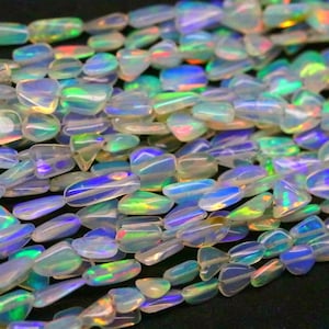 May include: Strands of iridescent opal beads. The beads are a mix of clear and opalescent colors, with flashes of blue, green, and yellow. The beads are smooth and polished, and appear to be strung together.