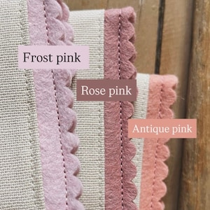 May include: Close-up of three fabric samples with scalloped edges in frost pink, rose pink, and antique pink. The samples are sewn onto a beige fabric. Text labels identify each color.