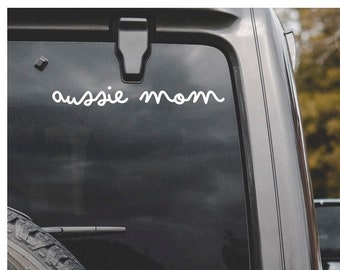 May include: A black car with a white vinyl sticker on the back window that says "aussie mom".