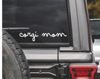 May include: A black car with a white vinyl decal on the back window that says "corgi mom".