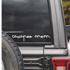 May include: A black car with a white vinyl decal on the back window that says "carpool mom".