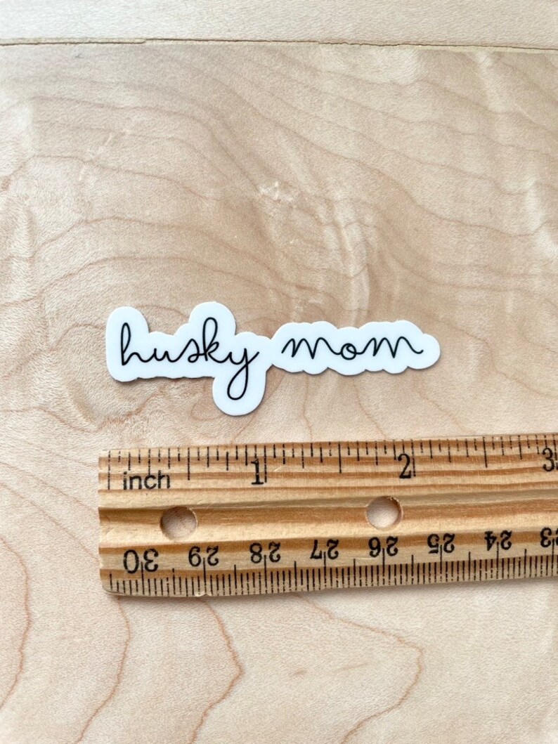 May include: White vinyl sticker with the text "husky mom" written in cursive.