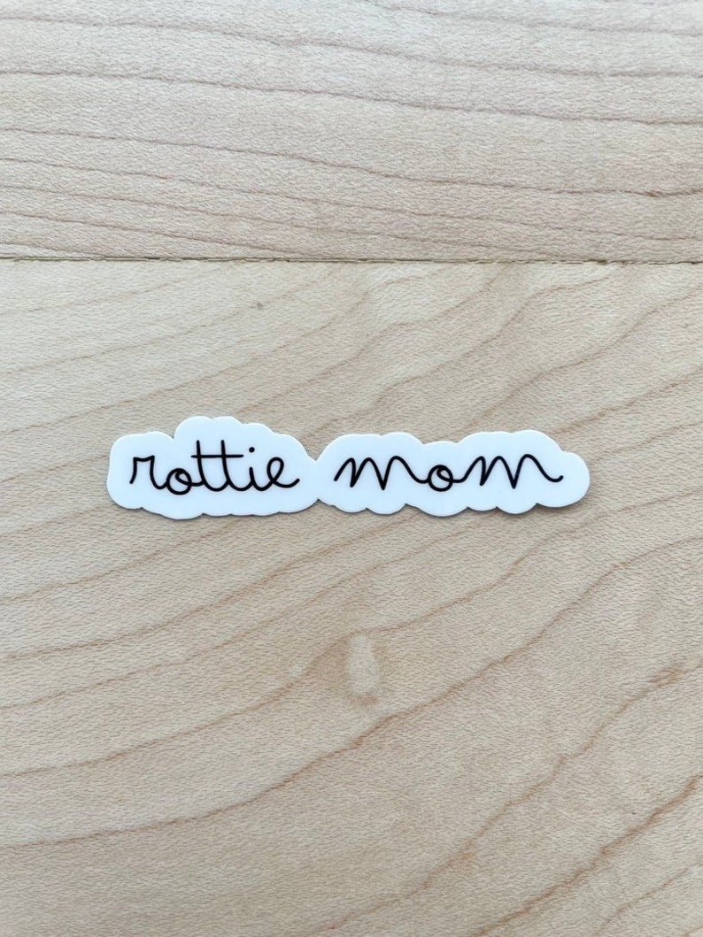 May include: White sticker with black cursive text that reads "rottie mom".
