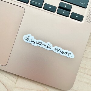 May include: A white sticker with black cursive text that reads "chiweenie mom" on a silver laptop.