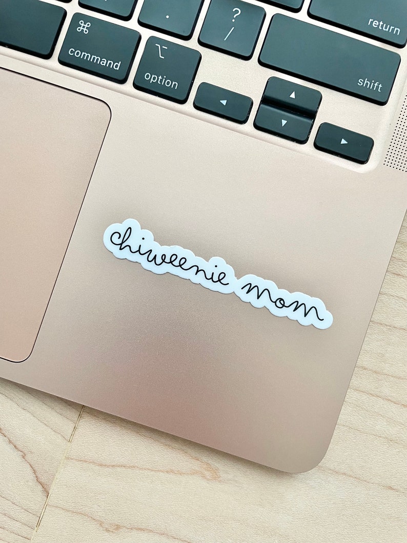 May include: A white sticker with black cursive text that reads "chiweenie mom" on a silver laptop.