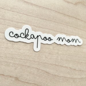 May include: White sticker with black cursive text that reads "cockapoo mom".
