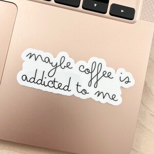 May include: A white sticker with black text that reads "maybe coffee is addicted to me" on a gold laptop.