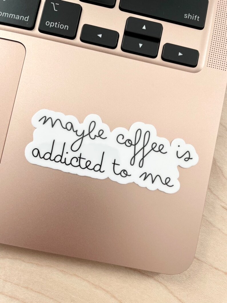 May include: A white sticker with black text that reads "maybe coffee is addicted to me" on a gold laptop.