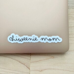 May include: A white sticker with black text that reads "chiweenie mom" on a light brown surface.