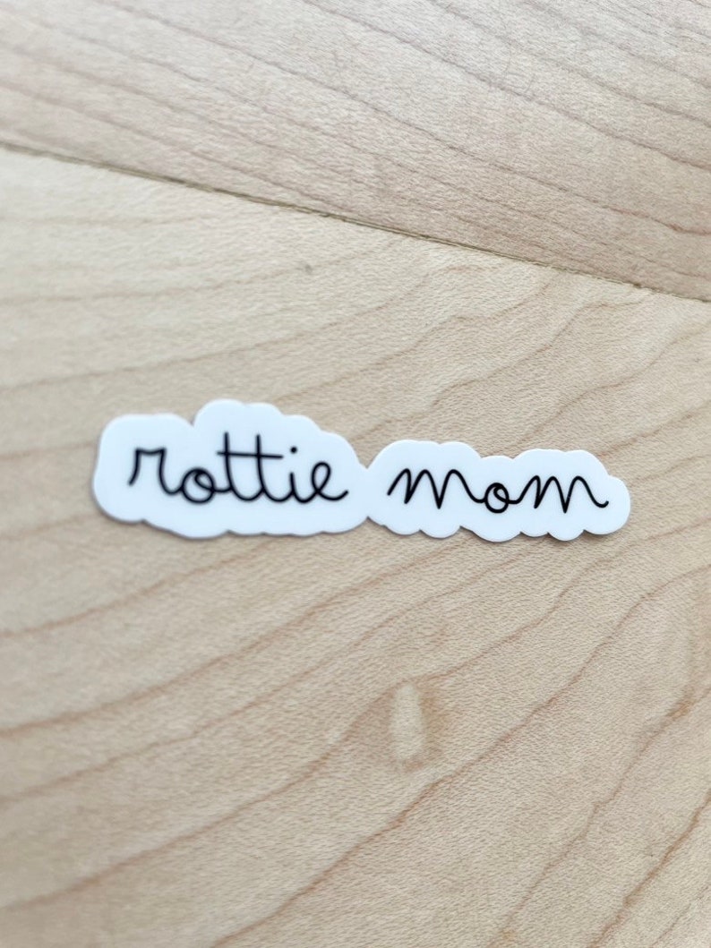 May include: White sticker with the text "rottie mom" written in black cursive.