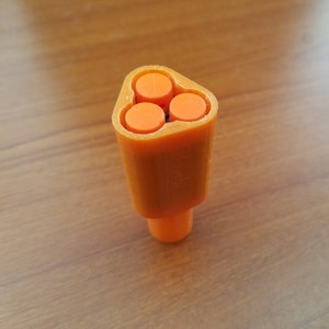 May include: Orange plastic nozzle with three round openings. The nozzle is shaped like a triangle.