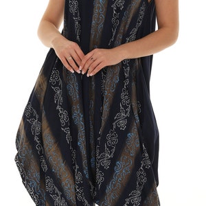 May include: A navy blue jumpsuit with a white floral pattern. The jumpsuit has a wide leg and a loose fit. The model is wearing gold sandals.