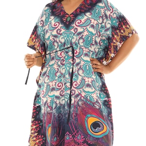 May include: A long, flowing kaftan dress with a peacock feather print in shades of blue, pink, and yellow. The dress has a V-neckline and a tie at the waist.
